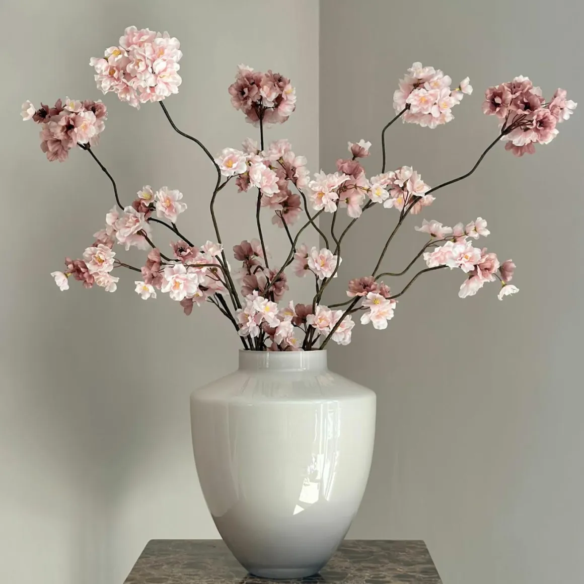 Beige vaas met roze zijden bloesemtakken